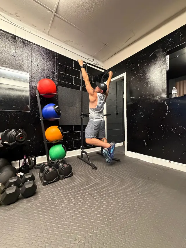 Adult client doing hanging knee raises on the pull-up bar