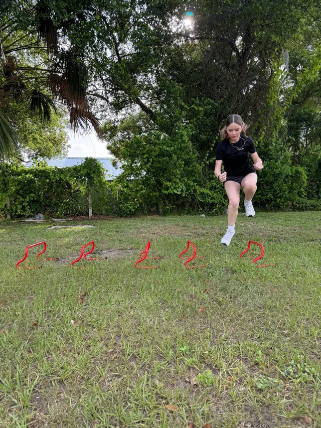 Athlete clearing a line of mini hurdles during an outdoor speed and plyometric drill